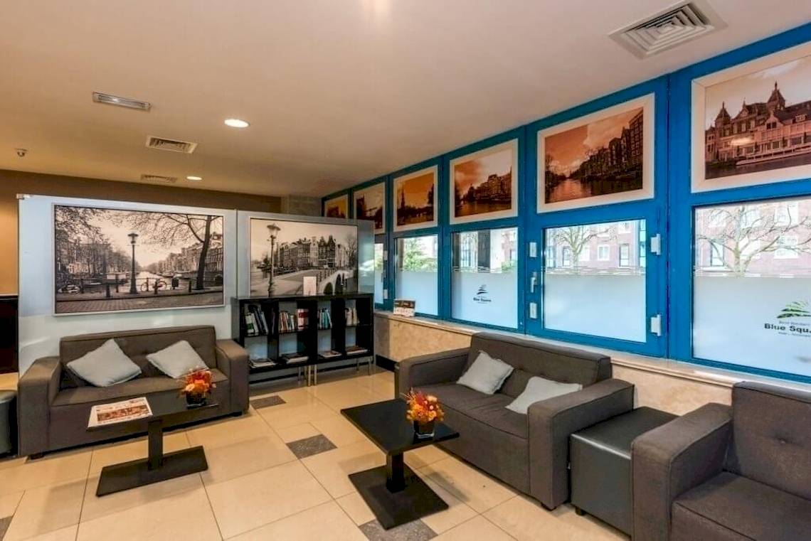XO Hotels Blue Square Lobby mit Sofas, Tischen und Gemälden an den Wänden.