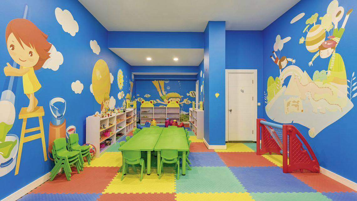 Kinderzimmer im Glamour Resort & Spa mit blauen Wänden, buntem Boden und Spielmöbeln.