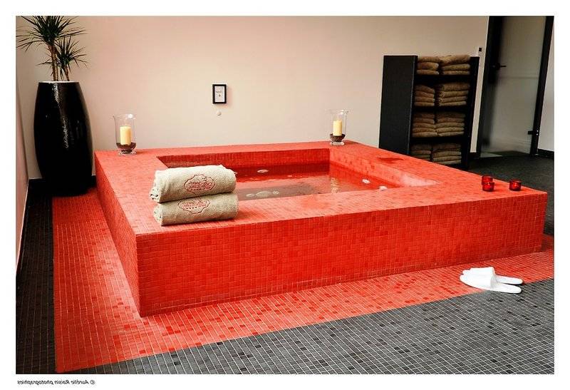 Roter Whirlpool im Boutique Hotel Liberata mit roten Kacheln und zwei Handtüchern.