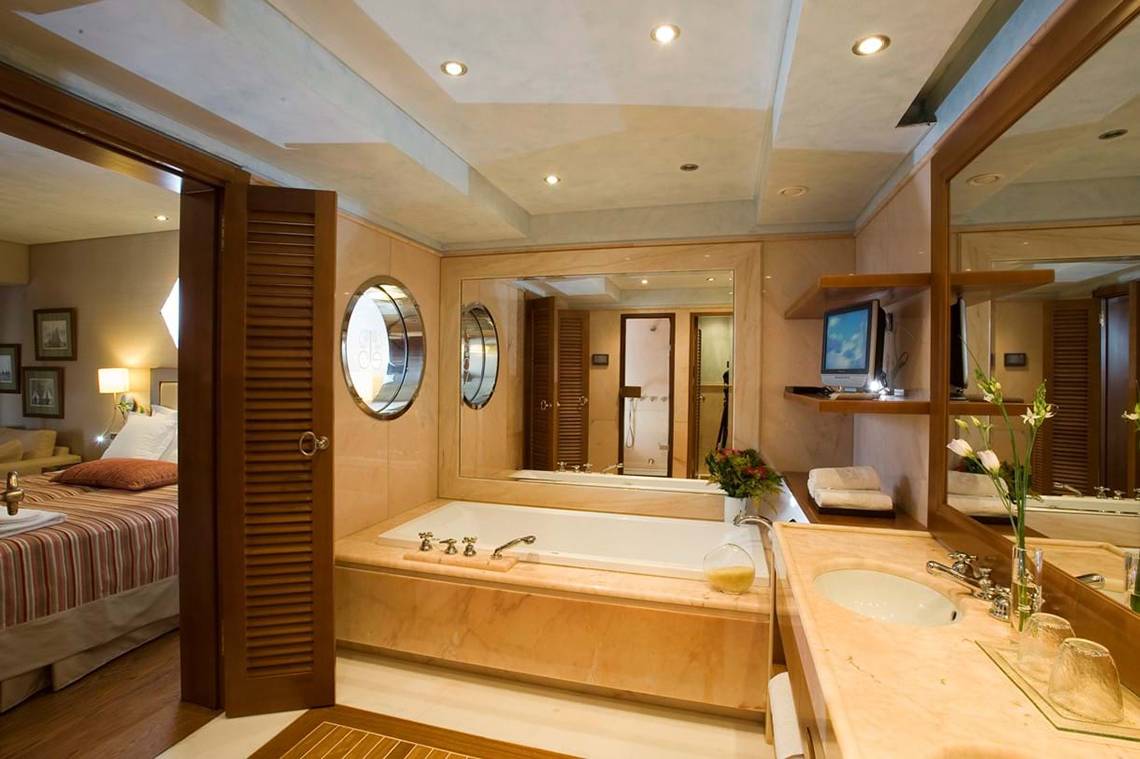 Badezimmer der Suite im Elounda Bay Palace Hotel mit Badewanne, Spiegel und Fernseher.
