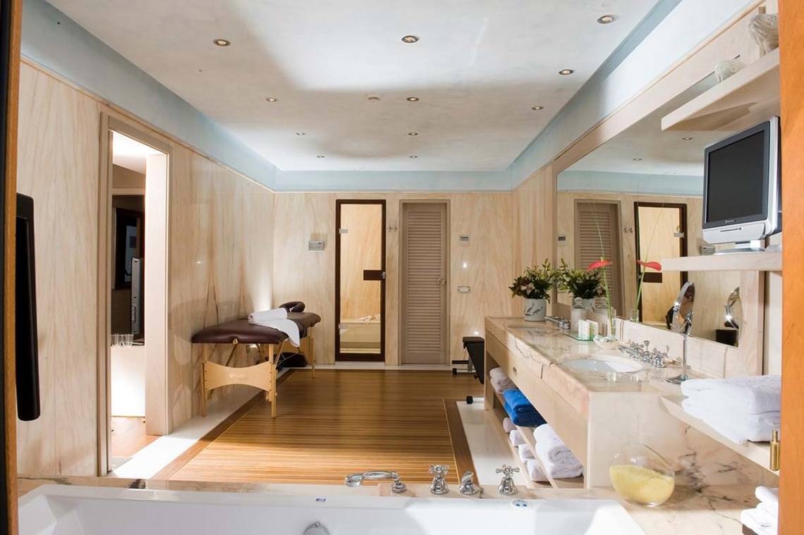 Luxuriöses Badezimmer im Elounda Bay Palace Hotel mit Badewanne, Dusche und Fernseher.