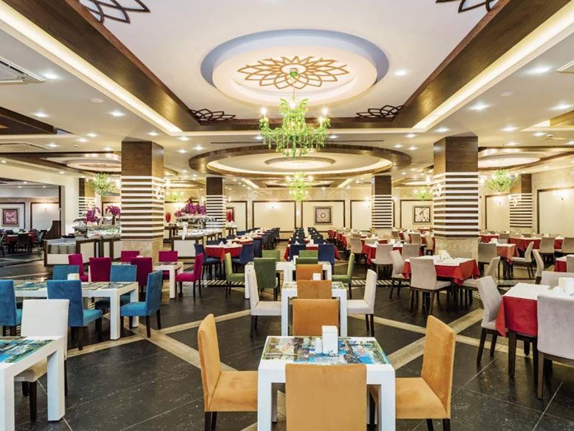 Innenansicht des Restaurants im Primasol Hane Family Resort mit bunten Tischen und Stühlen.