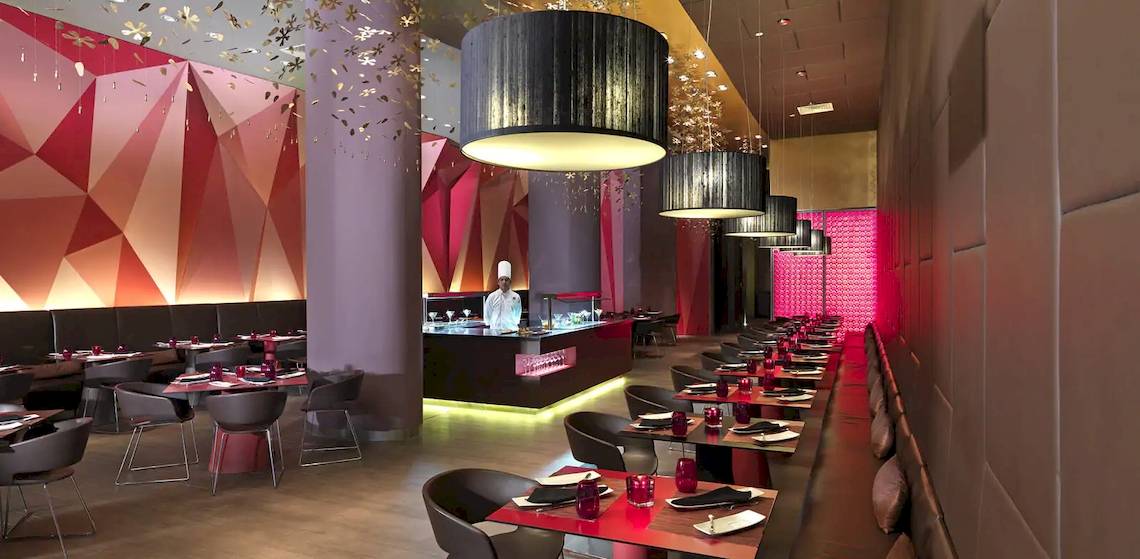Innenansicht des Restaurants im Paradisus Playa del Carmen mit modernem Design und einem Koch am Tresen.