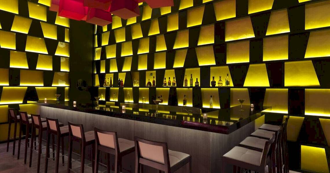 Innenansicht der Bar im Paradisus Playa del Carmen Hotel mit gelben Wandverkleidungen und Theke.