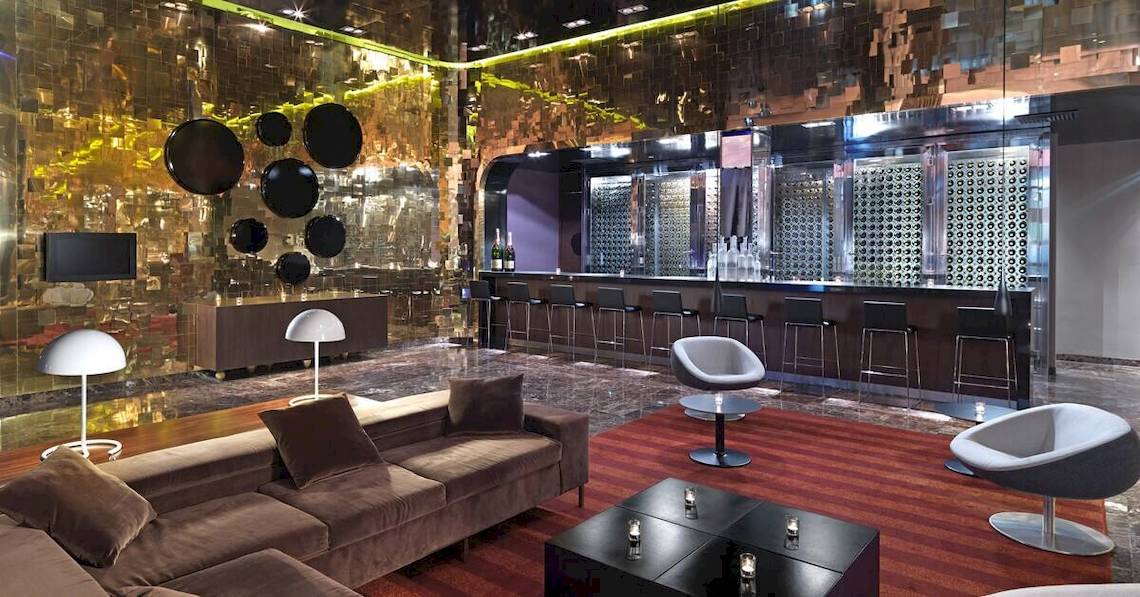 Innenansicht der Lobby im Paradisus Playa del Carmen Hotel mit goldenen Wänden, moderner Bar und Möbeln.