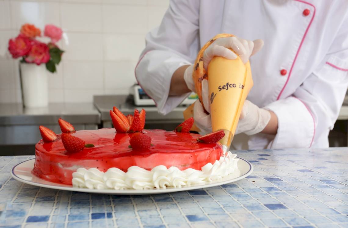 Koch dekoriert Kuchen mit Erdbeeren und Sahne im Paradise Hotel Corfu