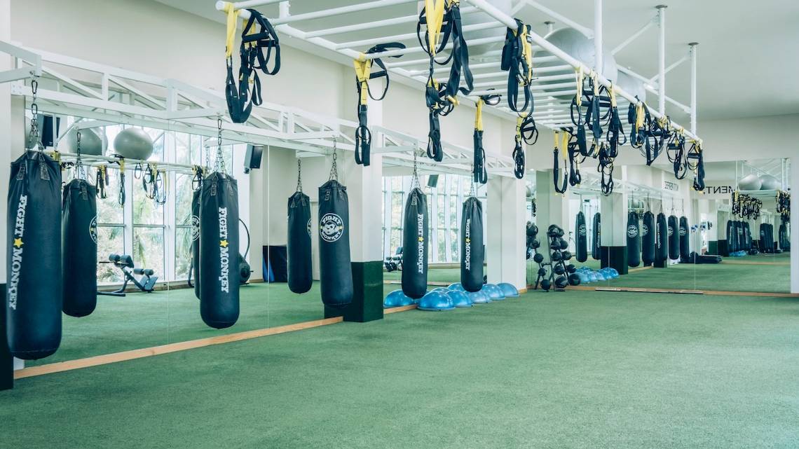 Fitnessstudio mit Boxsäcken und Trainingsgeräten an der Decke hängend.