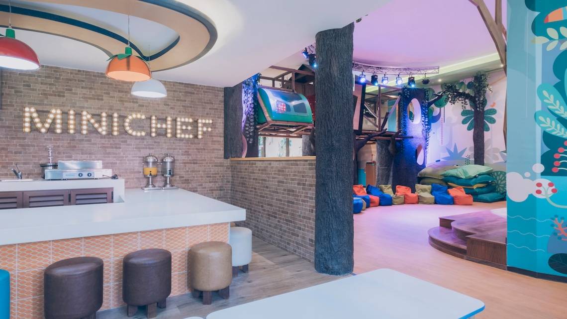 Innenbereich des Iberostar Paraiso del Mar Mini Chef Bereich mit gemauerter Wand, Bar, Stühlen und bunter Bemalung.