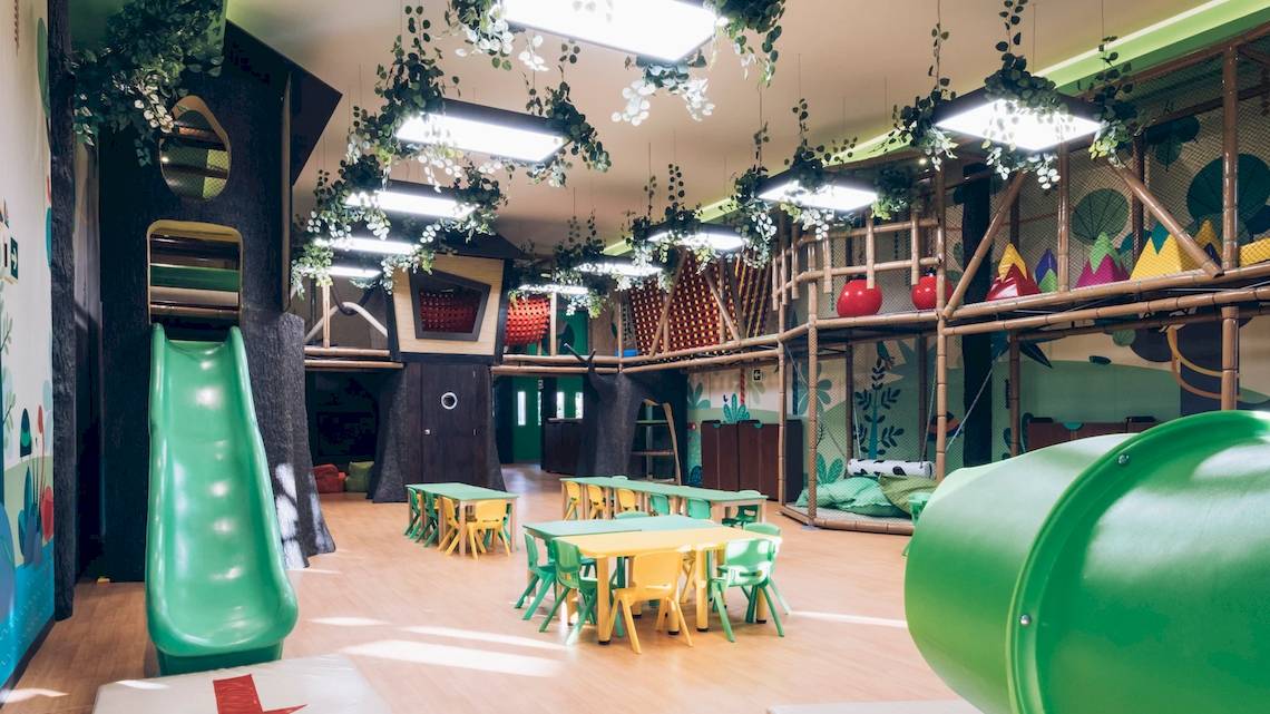 Der Kinderspielbereich des Iberostar Paraiso del Mar mit bunten Farben, Tischen, Stühlen und Spielgeräten.