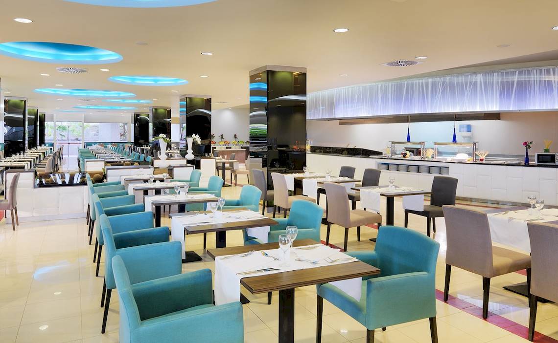 Innenansicht des Restaurants im H10 Playa Meloneras Palace Hotel mit blauen Stühlen und Tischen.