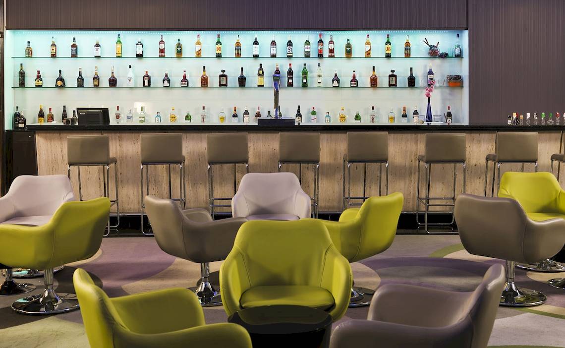 Innenansicht der Bar im H10 Playa Meloneras Palace mit vielen Getränkeflaschen und verschiedenen Stühlen.