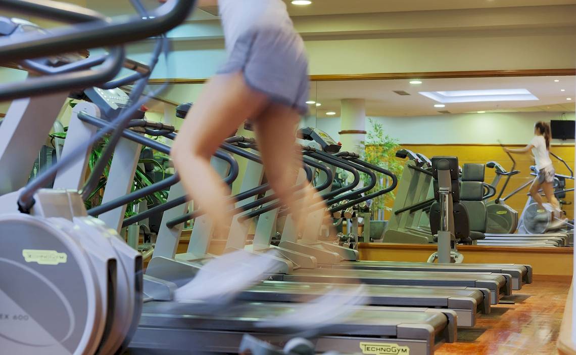 Fitnesscenter im H10 Playa Meloneras Palace mit mehreren Laufbändern, eine Person in Bewegung.