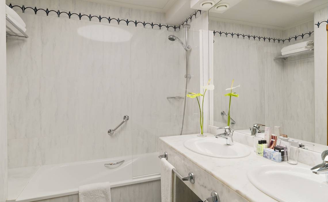 Badezimmer im H10 Playa Meloneras Palace mit Badewanne, Dusche, Waschbecken und Spiegeln.