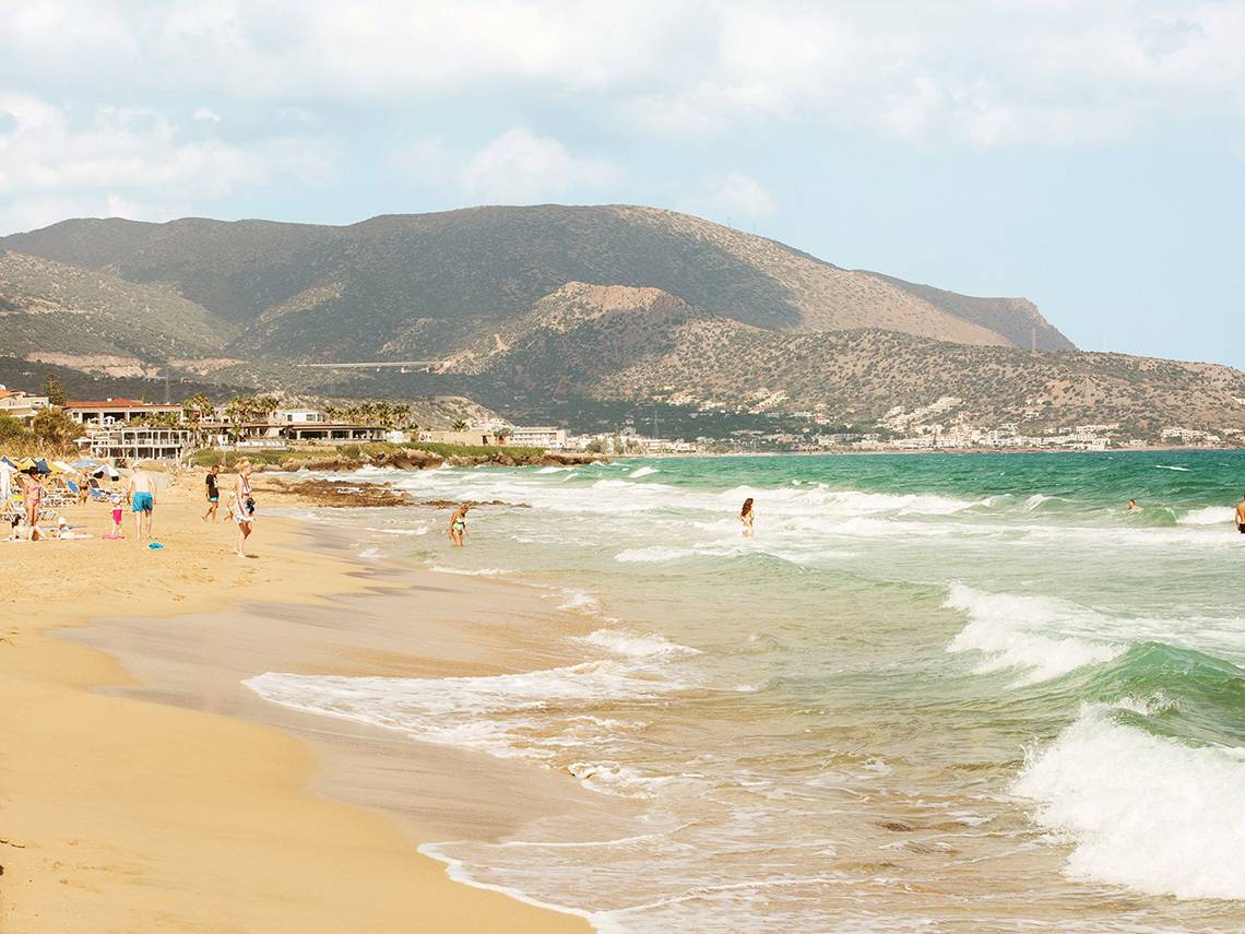 Strandlandschaft des Blue Sea Beach Affiliated by Melia mit Menschen und Bergen im Hintergrund.