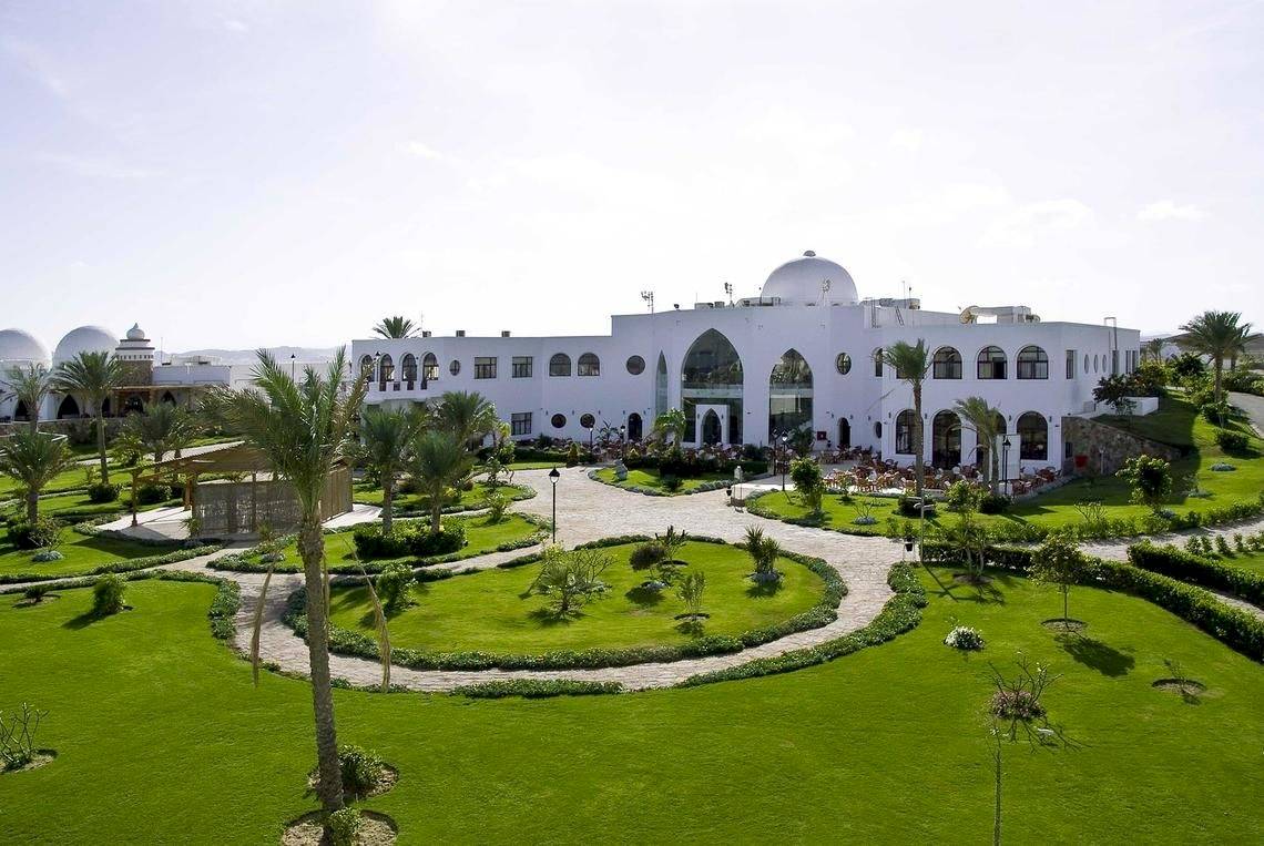 Luftaufnahme des Gorgonia Beach Resorts mit gepflegtem Garten und mehreren Palmen.
