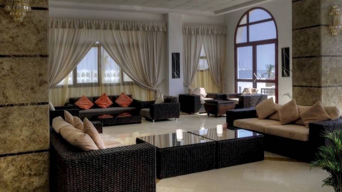 Hotellobby des Gorgonia Beach Resorts mit Sofas, Tischen und großen Fenstern.