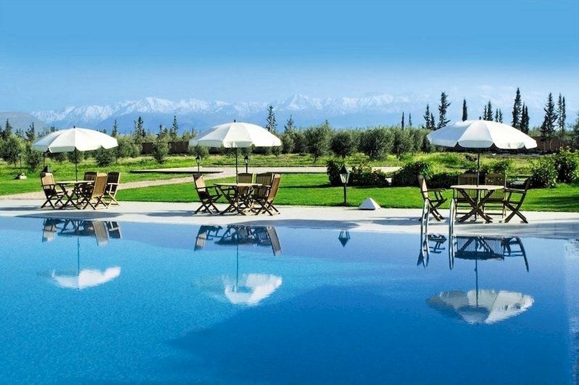 Außenpool des Pickalbatros Aqua Fun Club mit Tischen und Stühlen unter weißen Sonnenschirmen.