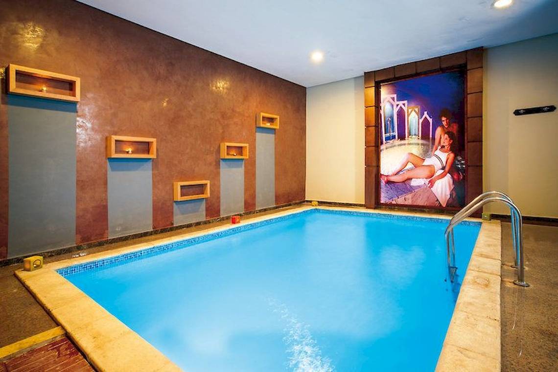 Innenpool des Pickalbatros Aqua Fun Clubs mit blauem Wasser und gerahmten Bildern an der Wand.