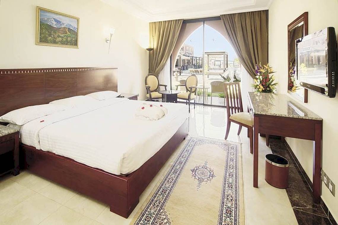 Hotelzimmer im Pickalbatros Aqua Fun Club mit großem Bett, Schreibtisch und Blick auf den Garten.