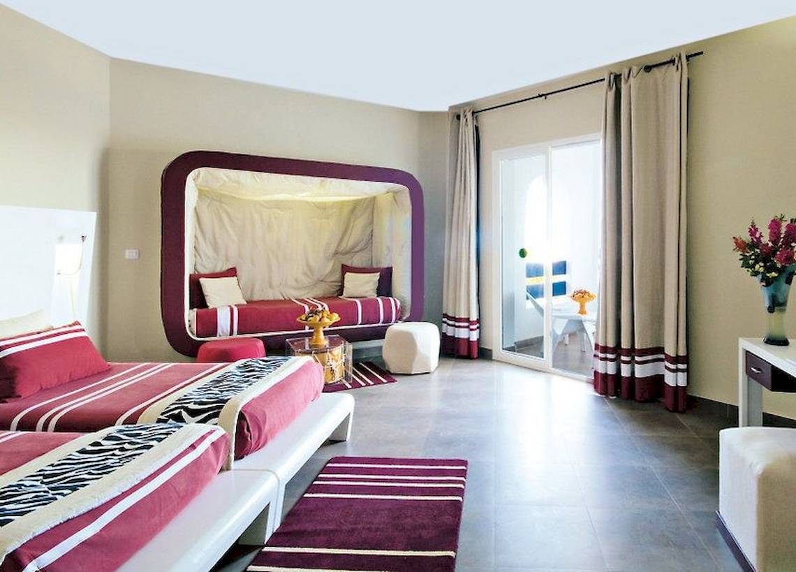 Schlafzimmer im Fiesta Beach Djerba Hotel mit zwei Betten, einem Baldachin und einer Glastür.