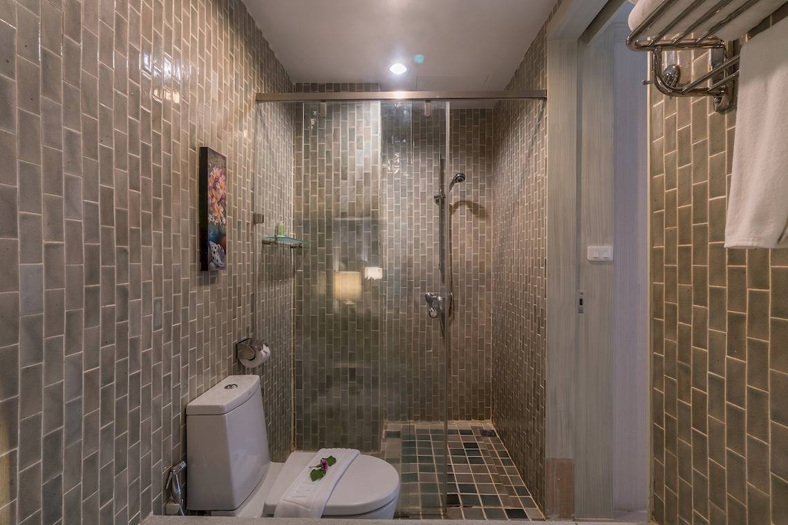 Dusche im Briza Beach Resort mit Fliesenwänden, Glasdusche und Toilette.