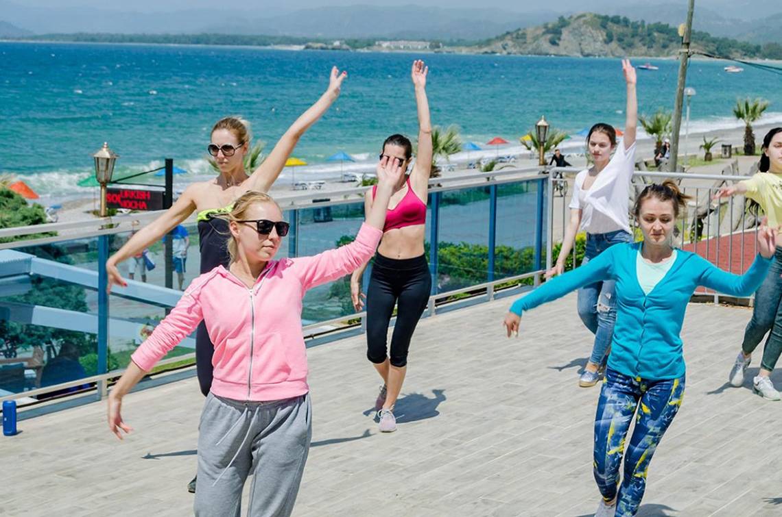 Frauen nehmen an einem Aerobic-Kurs auf der Terrasse eines Hotels am Strand teil