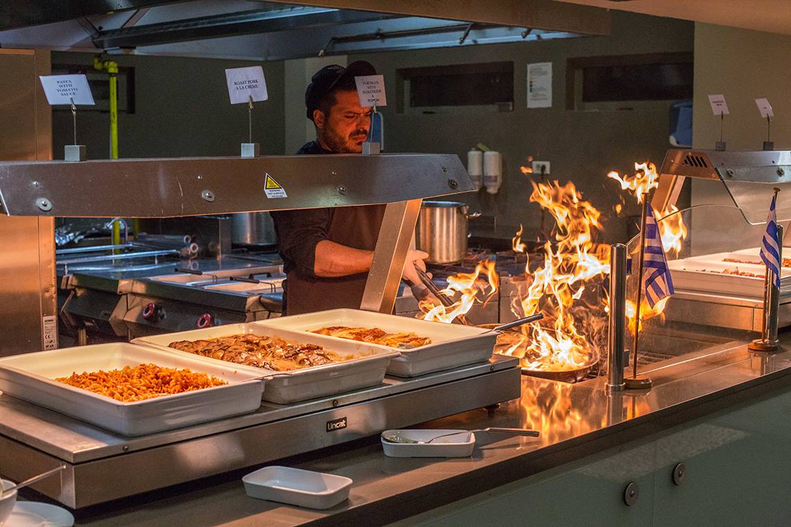 Ein Mann grillt Essen in einem Restaurant des Akti Imperial Deluxe Resort & Spa.