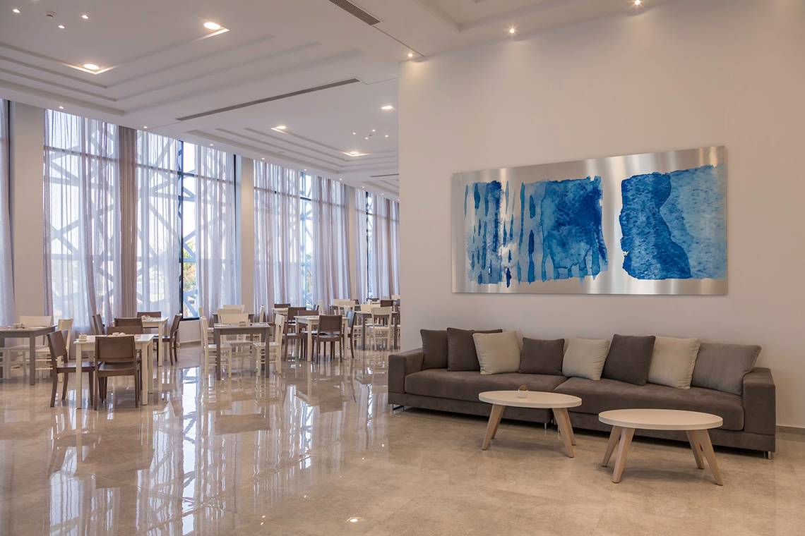 Loungebereich eines Hotels mit einem Sofa, zwei kleinen Tischen und einer großen Wandkunst.