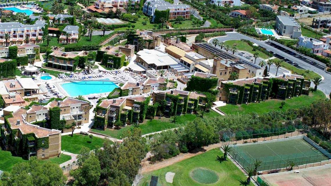 Außenansicht des Bella Beach Hotels mit Swimmingpool, Tennisplatz und umliegender Landschaft