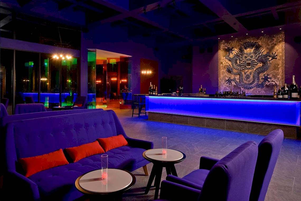 Loungebereich im Kandima Maldives Hotel mit blauer Beleuchtung und einem Drachenwandbild.