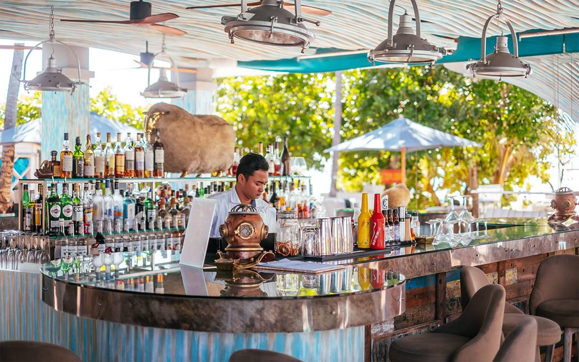Ein Barkeeper serviert Getränke hinter einer Theke im Freien im Finolhu Baa Atoll Hotel auf den Malediven.
