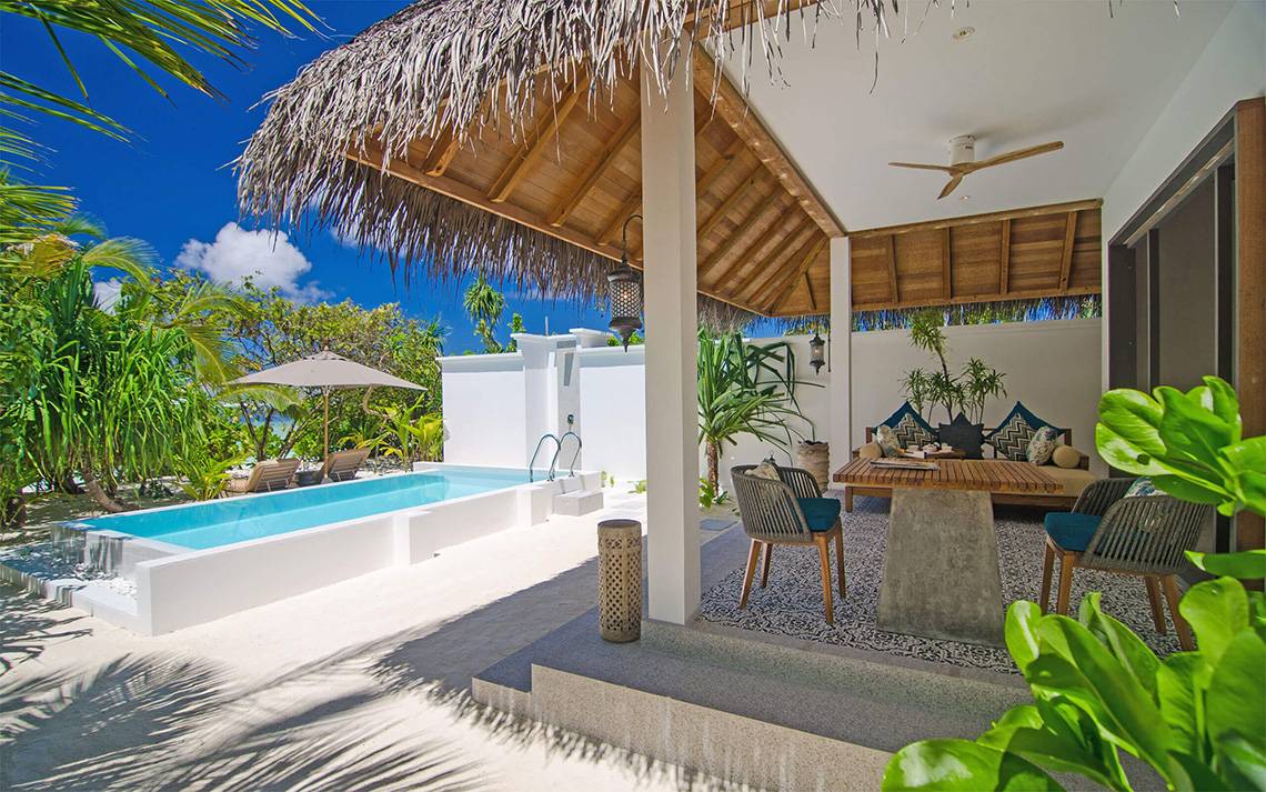 Außenpool und Terrasse des Finolhu Baa Atoll Maldives Hotels mit Loungemöbeln und Pflanzen.