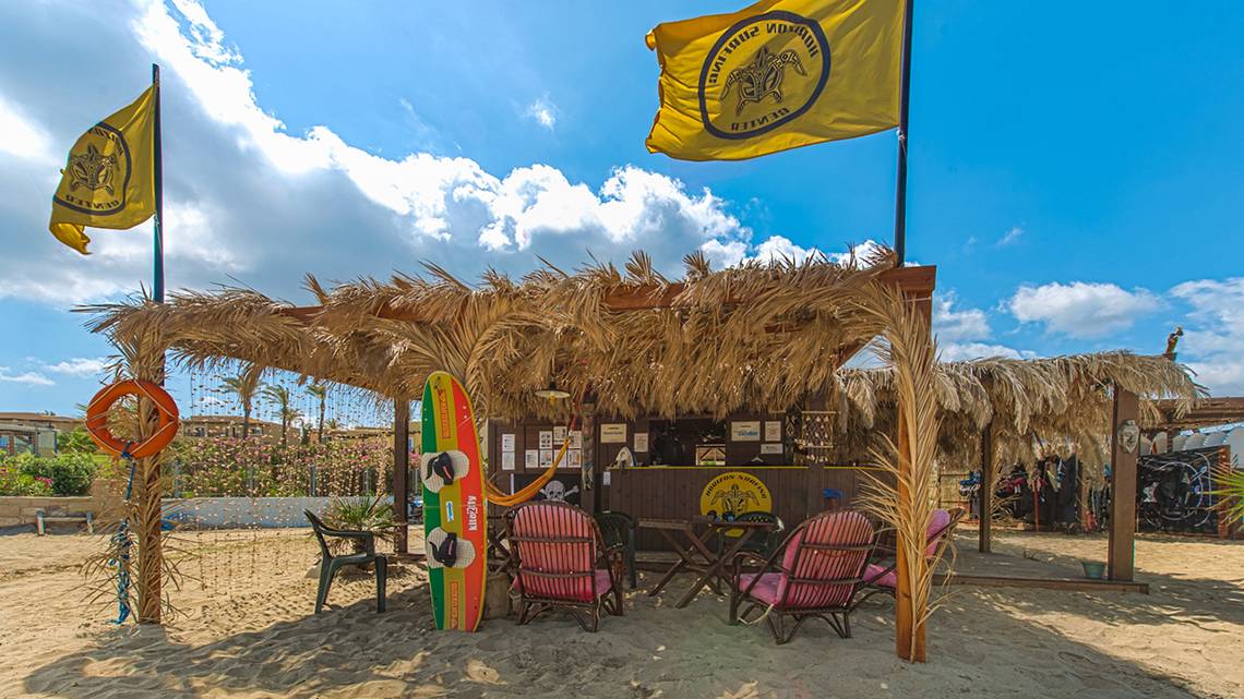 Strandstand des Horizon Beach Resorts mit Palmenblätterdach, Flaggen und Strandmöbeln.