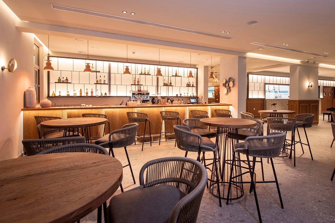 Barbereich im Horizon Beach Resort mit Holztischen, Stühlen und einer Bar.