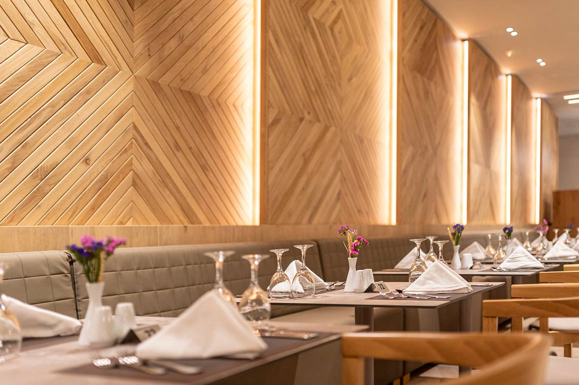Innenansicht des Restaurants im Horizon Beach Resort mit gemusterten Holzwänden und gedeckten Tischen.