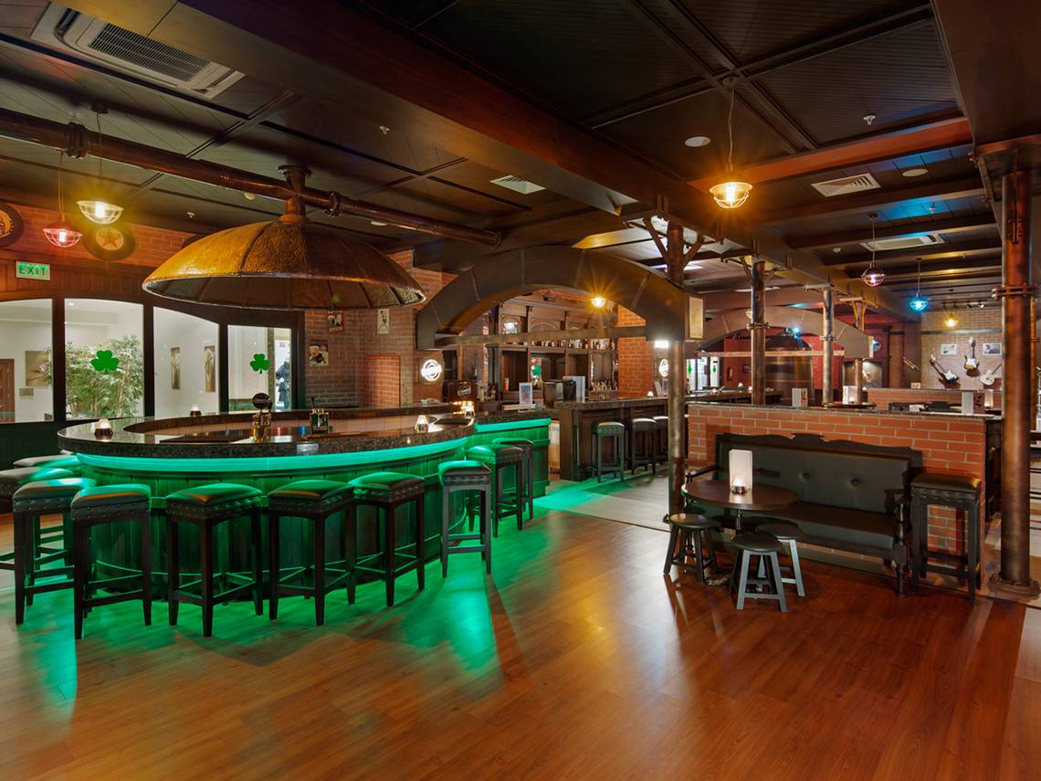 Innenbereich der Bar im Diamond Excellence Resort & Spa mit grüner Beleuchtung und Holzboden.