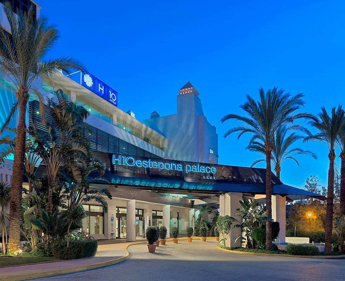 Eingang des H10 Estepona Palast Hotels mit Palmen und Beleuchtung