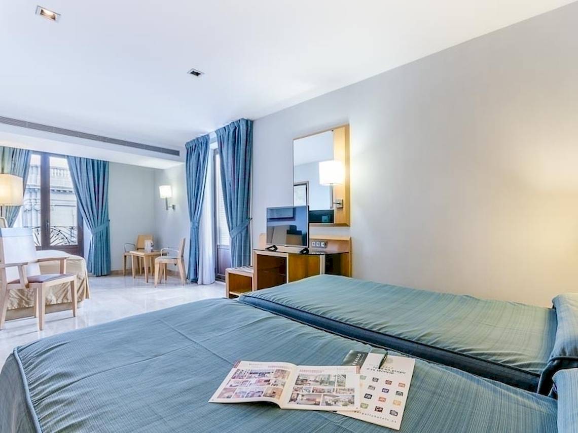 Schlafzimmer im Del Mar - Barcelona Hotel mit zwei Betten, Zeitschriften, und Möbeln