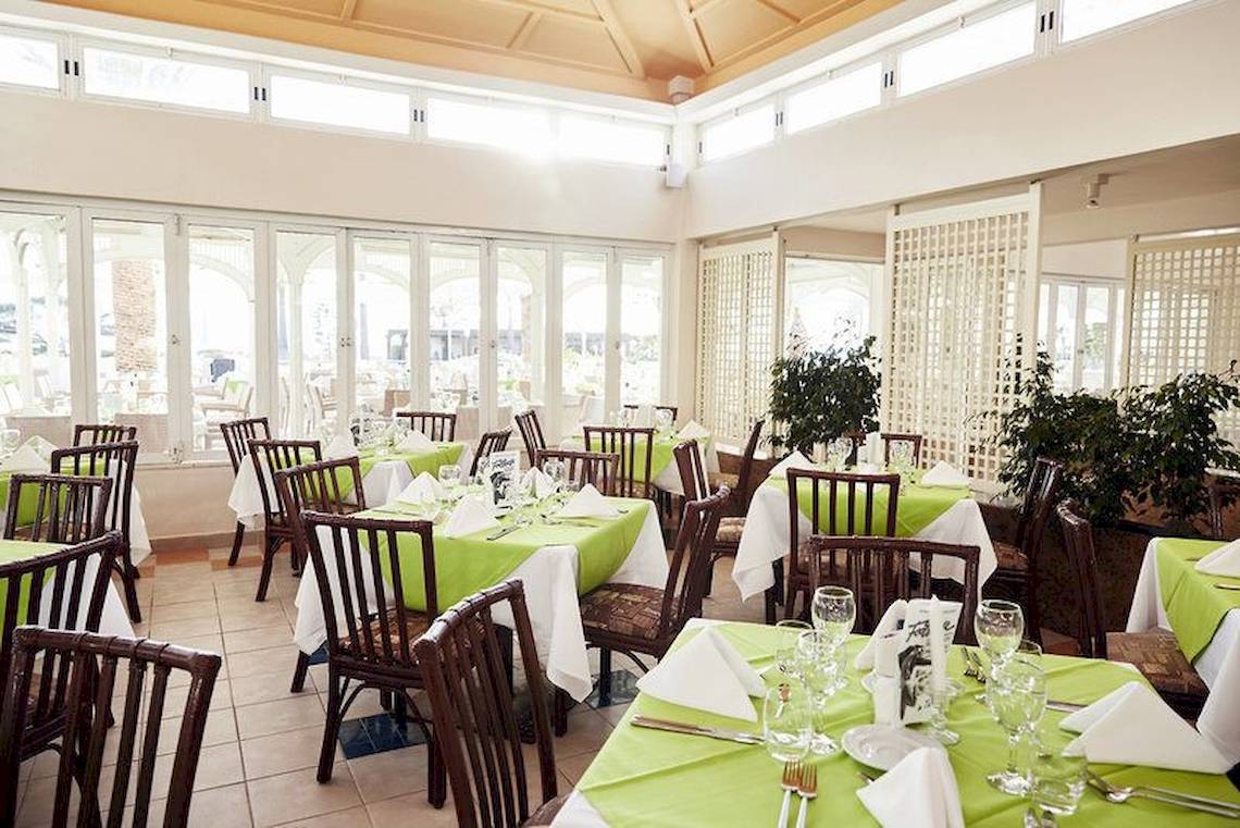 Restaurant im Robinson Kyllini Beach Hotel mit grünen Tischdecken und braunen Stühlen.