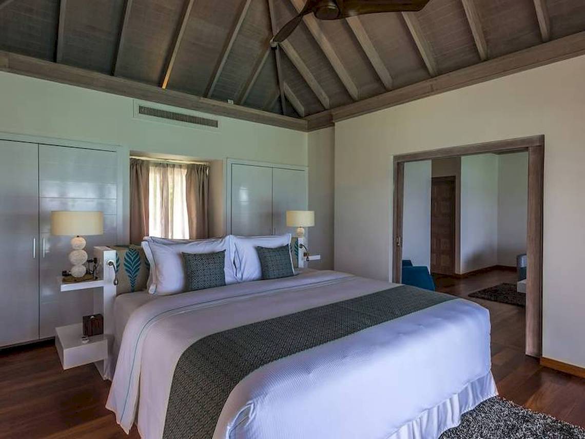 Schlafzimmer im Amaya Kuda Rah Hotel mit großem Bett, Lampen und Holzboden.