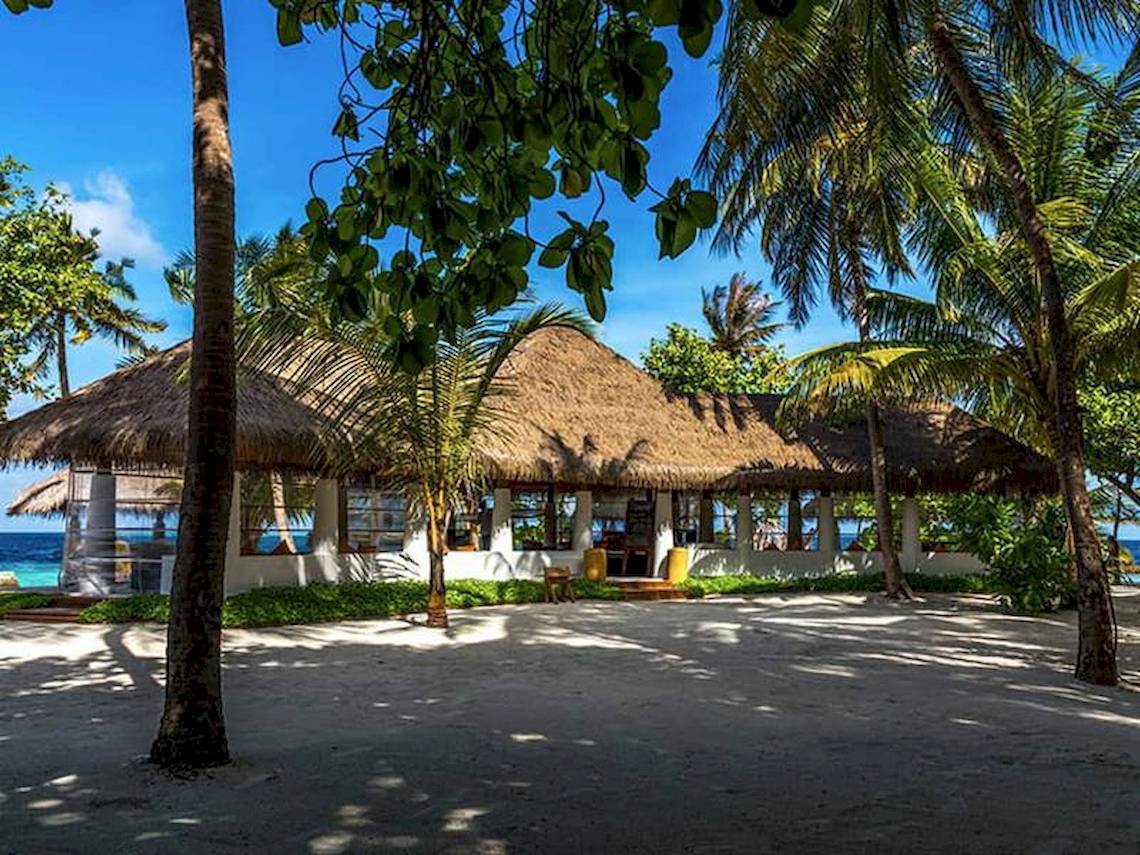 Das Amaya Kuda Rah Hotel mit einem großen, strohgedeckten Dach vor einer Palmenlandschaft.