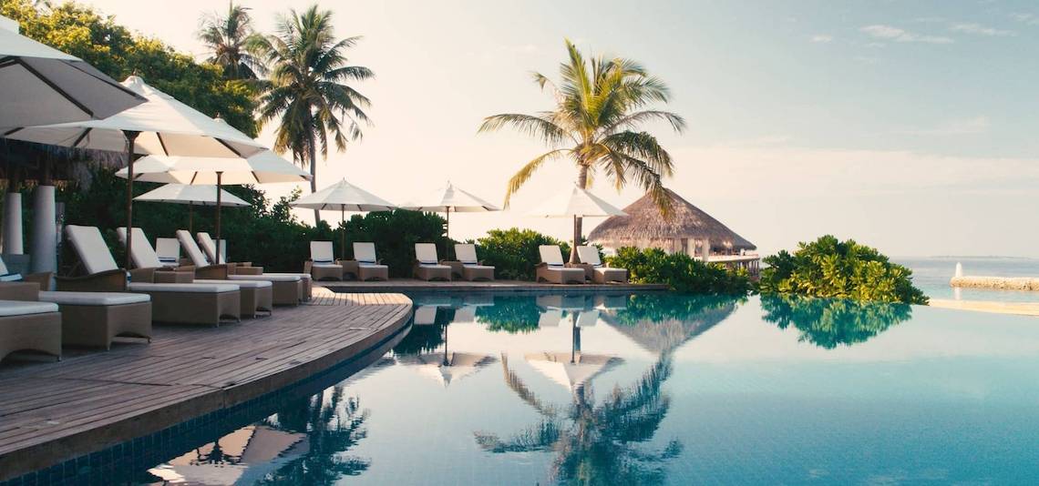 Pool-Loungebereich im Amaya Kuda Rah Hotel mit Sonnenliegen und Sonnenschirmen.