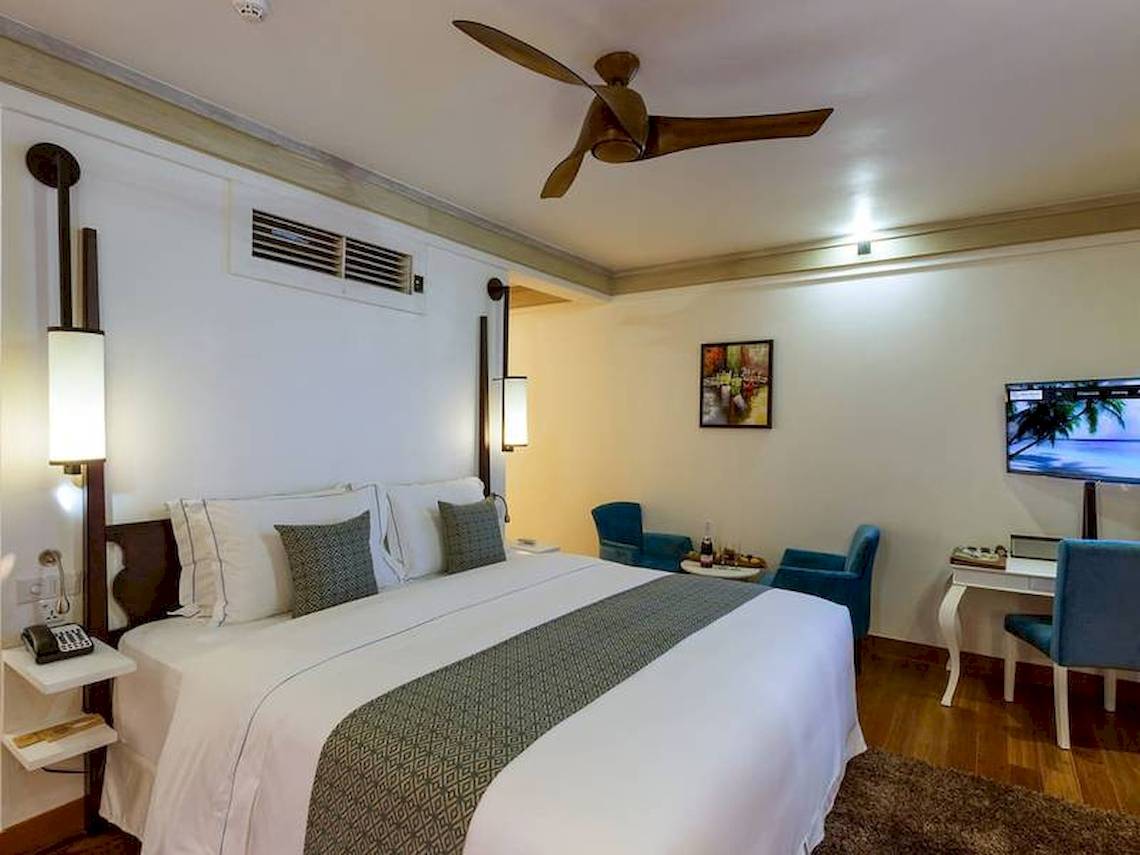 Hotelzimmer von Amaya Kuda Rah mit Doppelbett, Fernseher, und Arbeitsbereich.