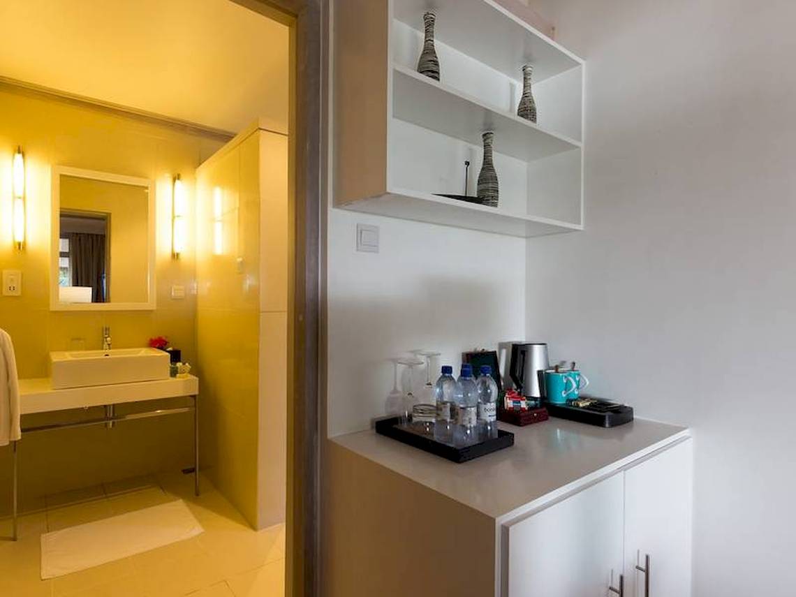 Innenansicht des Badezimmers im Amaya Kuda Rah Hotel mit gelben Wänden, weißem Waschbecken und Regal.