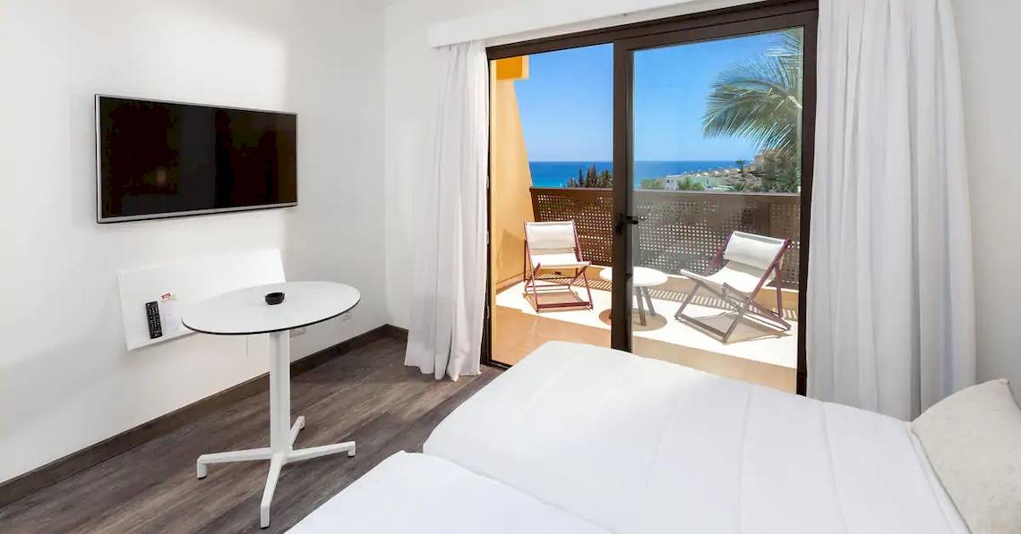 Ein Zimmer im Sol Fuerteventura Jandia Hotel mit Balkon, Fernseher, Tisch und Stühlen.