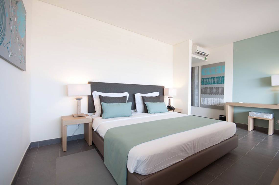 Doppelbett im Hotelzimmer Oasis Salinas Sea mit moderner Einrichtung und weißen Wänden.