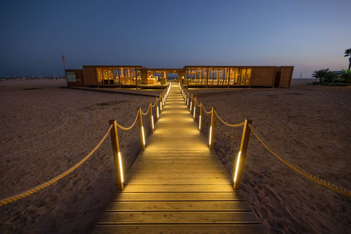 Nachtansicht des Oasis Salinas Sea Hotels am Strand mit beleuchtetem Holzsteg.