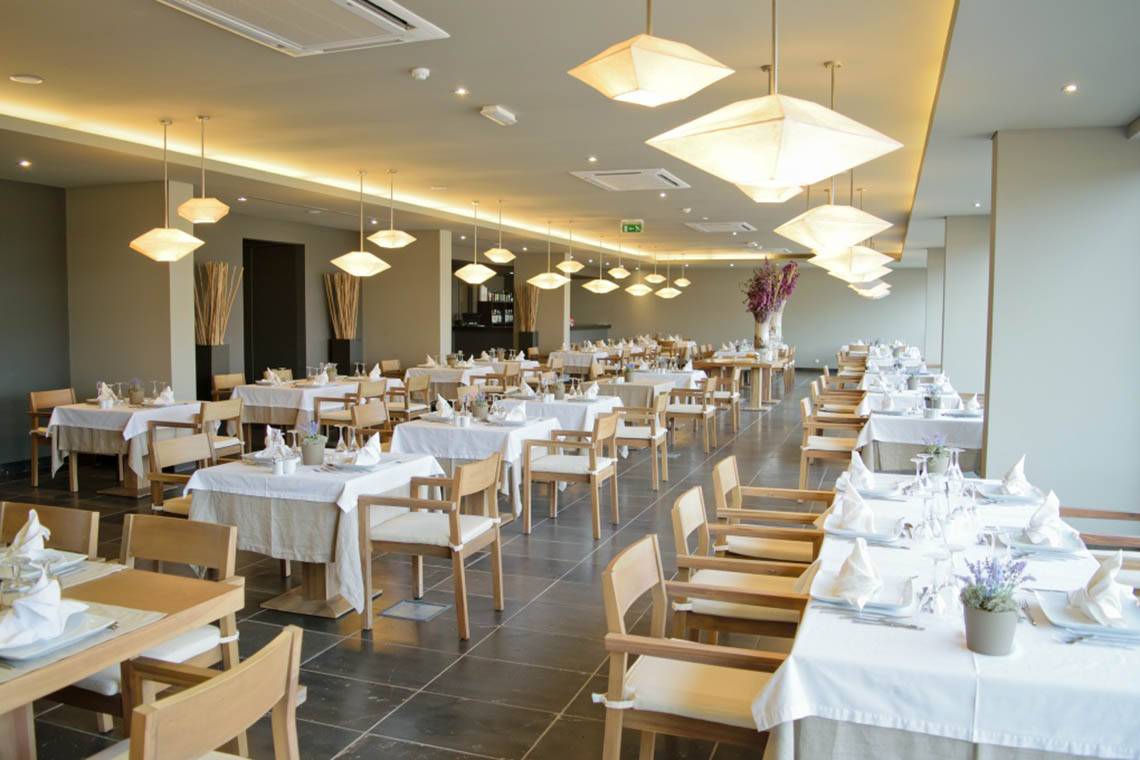 Innenansicht des Restaurants im Oasis Salinas Sea Hotel mit gedeckten Tischen und dekorativen Lampen.