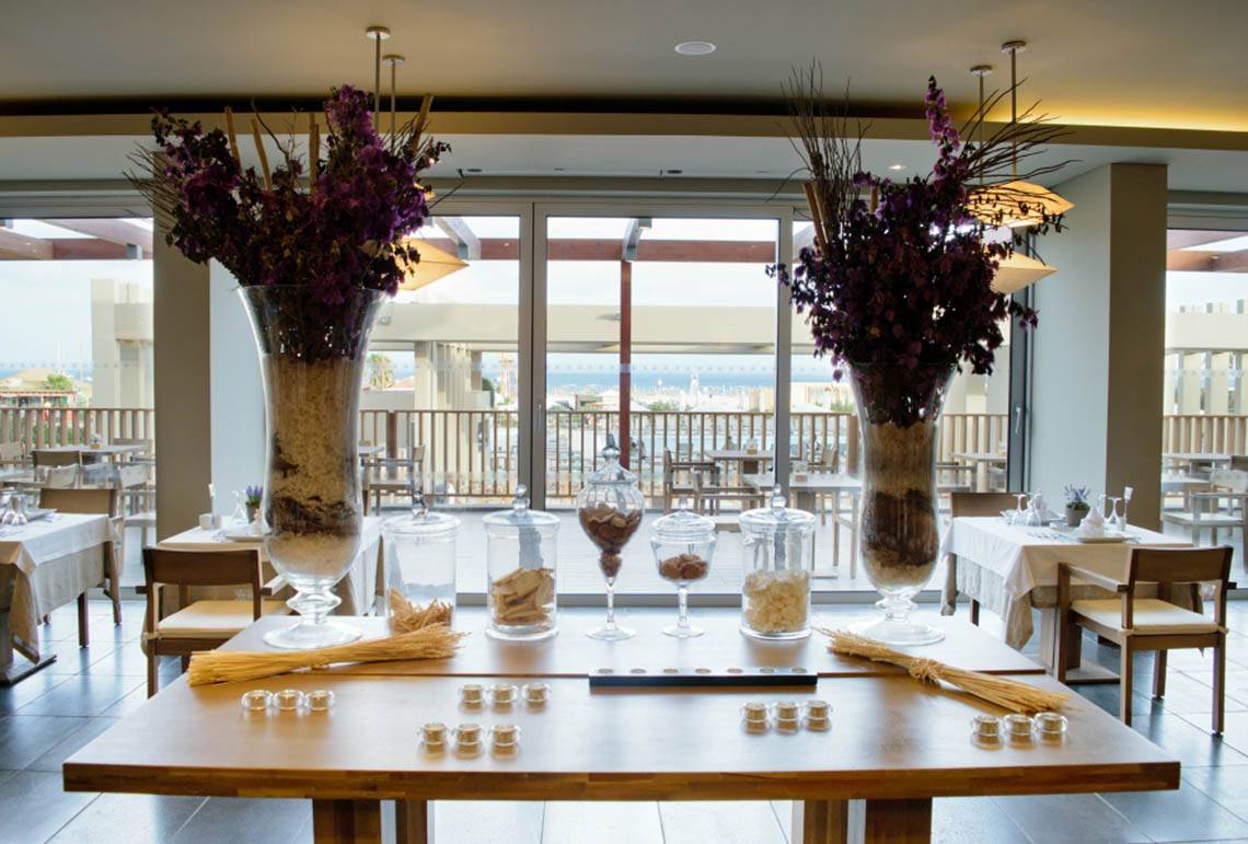 Innenansicht des Restaurants Oasis Salinas Sea mit Tischdekoration und Blick auf das Meer.