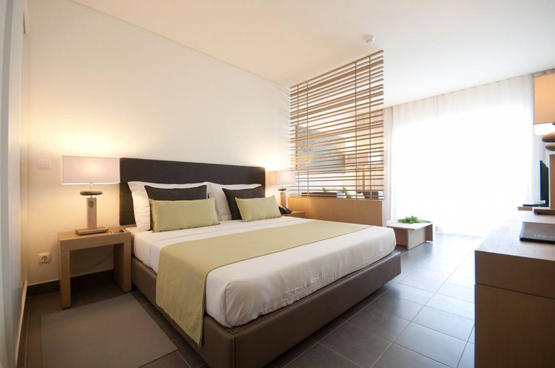 Modernes Schlafzimmer im Oasis Salinas Sea Hotel mit Bett, Nachttischen und Lampen.